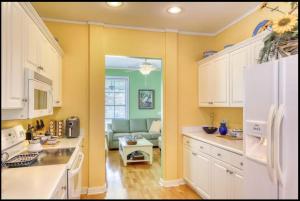 a kitchen with yellow walls and white cabinets at Bay Breeze - 3 Min Walk to Beach in Tybee Island +21 photos