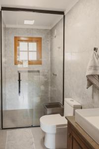 a bathroom with a toilet and a glass shower at Casa, sítio, aconchegante no Vale dos Vinhedos. in Bento Gonçalves