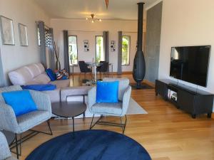 un salon avec des chaises bleues et une télévision dans l'établissement Villa Palmera Sea View, à Arco da Calheta