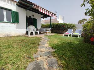 a patio with chairs and a table in a yard at private Bungalow next to Yumbo Center in Playa del Ingles