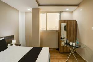 ラクナウにあるHotel O Raisi Residency Hotelのベッドとガラスのテーブルのある寝室