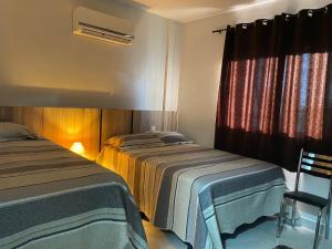 a bedroom with two beds and a window and a chair at Lagoa Quente Flat in Caldas Novas +18 photos