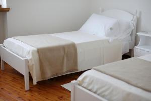 Habitación con 2 camas blancas y suelo de madera. en Casa Vacanze Selva en Premariacco