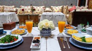 a table with plates of food and glasses of orange juice at Riad El Ouedghiri in Fez