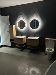 a bathroom with two sinks and a toilet and two mirrors at The Cleveland Retreat - sauna stay in Boosbeck