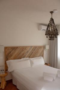 a bedroom with a white bed with a wooden headboard at Hostal La Torre Ibiza Cap Negret in San Antonio
