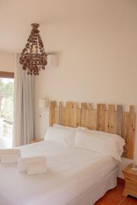 a bedroom with a large white bed and a chandelier at Hostal La Torre Ibiza Cap Negret in San Antonio