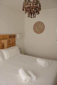 a bedroom with a white bed with two towels on it at Hostal La Torre Ibiza Cap Negret in San Antonio