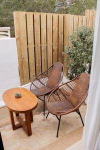 two chairs and a table on a patio with a fence at Hostal La Torre Ibiza Cap Negret in San Antonio