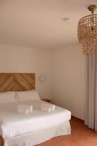 a bedroom with a white bed and a chandelier at Hostal La Torre Ibiza Cap Negret in San Antonio