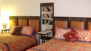 1 dormitorio con 2 camas y estante para libros en Lundeen Inn of the Arts, en Las Cruces