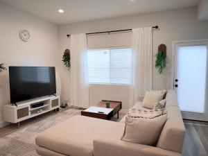a living room with a couch and a flat screen tv at Modern Family Haven - Minutes from Disney Magic-OC in Midway City