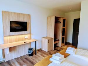 una stanza con un letto e una TV su una parete di Hotel Tausendschön a Südbrookmerland