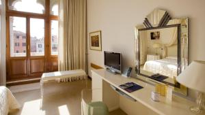 a hotel room with a bed, desk and mirror at Hotel Principe in Venice