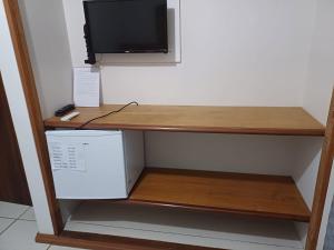 a desk with a television and a box on a shelf at Suítes da Penha in Capitólio