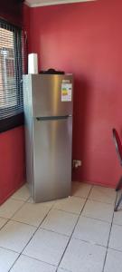 a refrigerator in a room with a red wall at Cabañas Buin in Puerto Montt