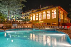 a swimming pool in front of a building at night at Balkan Hotel in Chiflik