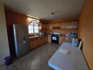 a kitchen with wooden cabinets and a stainless steel refrigerator at Cabaña el Pino in Penche Chico