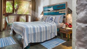 um quarto com uma cama com um cobertor azul e branco em Pescador - Pousada de Charme em Jericoacoara