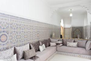 a living room with a couch and a wall with tiles at Dar Al Hajja Fatima in Rabat