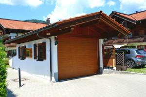 a house with a wooden garage with a roof at Ferienwohnung Sonnenwinkl in Reit im Winkl