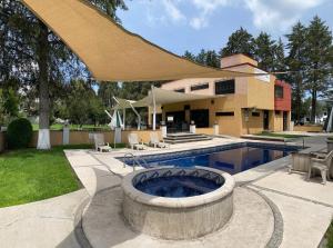 a patio with a pool and a large umbrella at Hotel Finca Las Hortensias in Tepotzotlán
