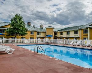 a pool at a hotel with chairs and a building at Baymont by Wyndham Harrisburg in Harrisburg