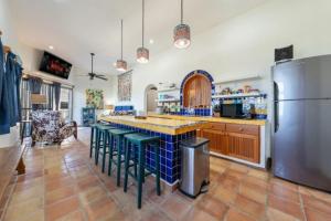 a large kitchen with a refrigerator and stools at Casa Amor Ocean Front Isla Mujeres in Isla Mujeres