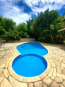 a large blue pool on a patio with a stone floor at Paraíso Geribá in Búzios