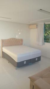 a bed in a white room with a couch at Familia Coutinho in Cayru