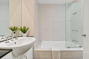 a white bathroom with a sink and a tub at Modern Comfort in the Heart of Sydney in Sydney +45 photos