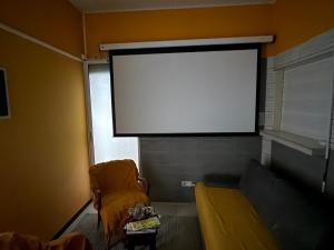 un grand écran dans un salon avec un canapé dans l'établissement residence caramboles, à Fort-de-France