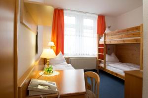 ein Hotelzimmer mit einem Schreibtisch und einem Etagenbett in der Unterkunft Hotel Heinz in Plauen