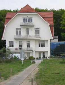 een groot wit huis met een rood dak bij Residenz am Strande in Warnemünde