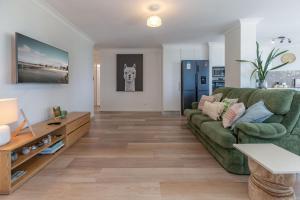 a living room with a green couch and a table at Heritage 301 in Tuncurry