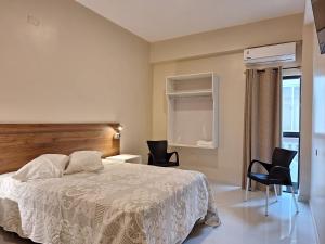 una camera da letto con un letto e due sedie di Hotel Brasil a Caazapa New