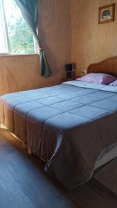 un letto grande in una camera da letto con finestra di Cabañas Kapüra a Hornopiren