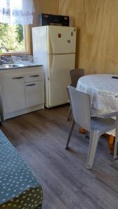 una cucina con un tavolo e un frigorifero bianco di Cabañas Kapüra a Hornopiren