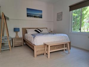 een slaapkamer met een bed, een tafel en een raam bij Forest view bungalow in Nambucca Heads