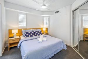 a bedroom with a bed and a table and windows at Ocean Front Mooloolaba Esplanade Apartment 2BR in Mooloolaba