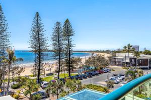 a view of a beach and a parking lot with cars at Ocean Front Mooloolaba Esplanade Apartment 2BR in Mooloolaba