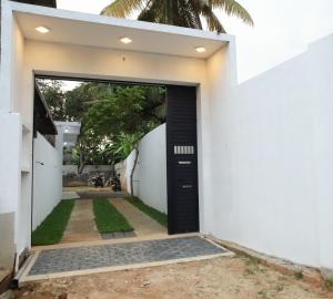 a black door in a white building with a yard at Villa Amber Breeze in Mirissa