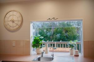 a kitchen with a sink and a clock and a window at Aotearoa Surf Lodge in Mangawhai