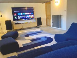 a room with two blue chairs and a large screen at Maison d'exception à 80m de la plage avec accès direct, proche commerces, terrasse, BBQ, WiFi inclus - FR-1-361-375 in Jullouville-les-Pins