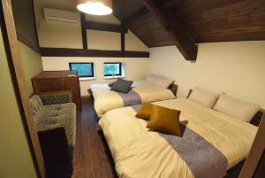 Una habitación con tres camas y una silla dentro. en 油屋別邸, en Beppu