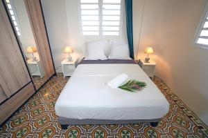 een slaapkamer met een groot wit bed met twee lampen bij Villa Amandine in Fort-de-France