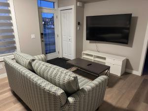 a living room with two chairs and a flat screen tv at Cozzy & Brand New Apartment, Near Banff Hwy in Calgary