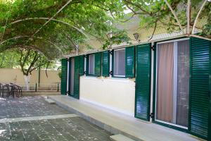 a building with green shuttered windows and a patio at Asterias in Koronisía