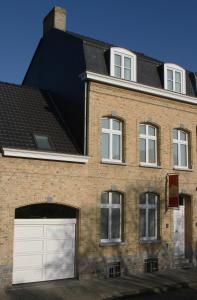 une maison en briques avec une porte de garage blanche dans l'établissement B&B @ Room's, à Ypres