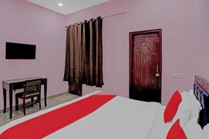 a bedroom with a bed and a table and a door at Hotel O AKKI RESIDENCY in Noida +14 photos
